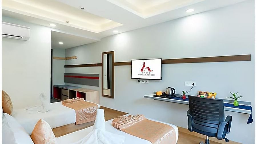 Relax in this airy twin room with two neatly arranged beds, soft color tones, and ample sunlight. Equipped with a TV, desk, and coffee maker for a comfortable and enjoyable experience.