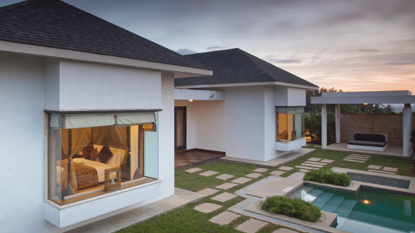 A modern resort villa at dusk with a private pool and a landscaped yard with stepping stones, located at The Serai Chikmagalur.