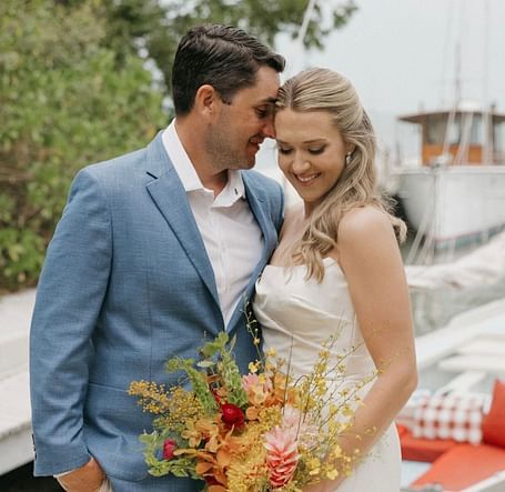 Bride and groom standing close, smiling and holding a vibrant bouquet of flowers at Casa Morada.