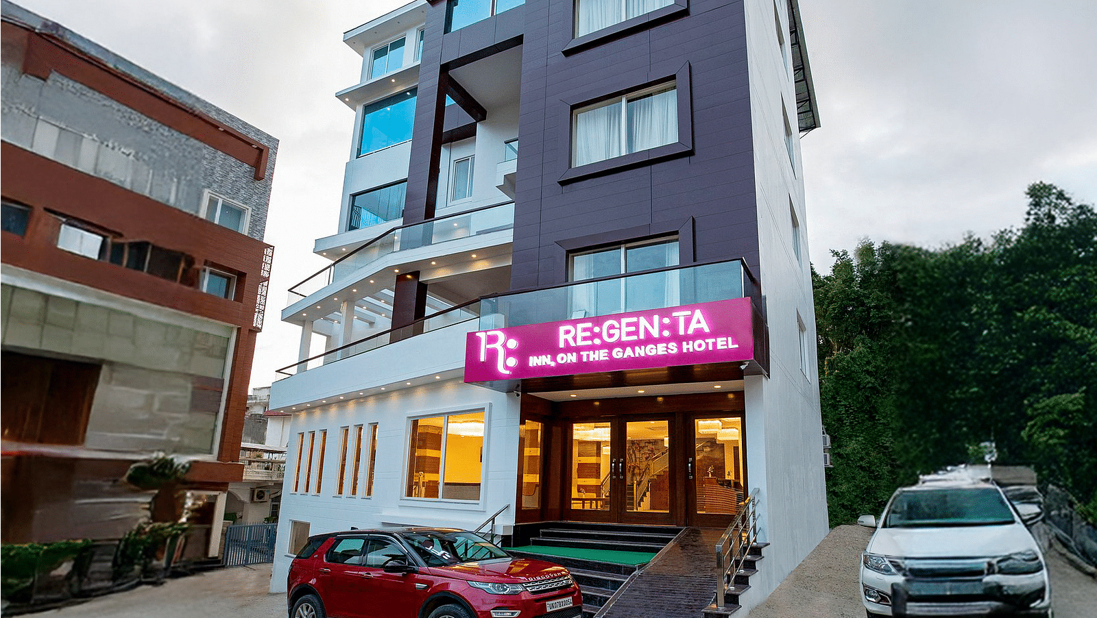 A wind angle shot of Regenta Inn DLS with a lush green hilly region in the background.