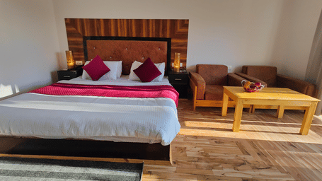 A wide-angle view of a  bedroom with parquet flooring and a seating area at Indus Serenity Retreat.