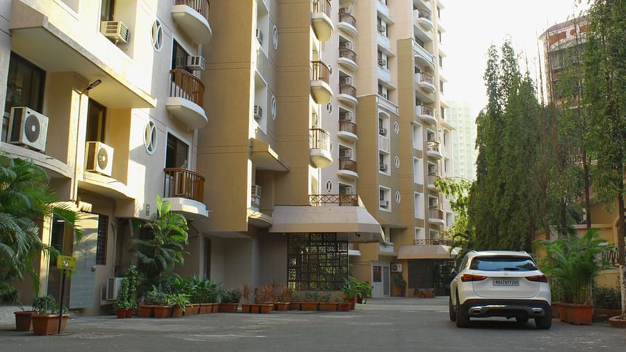 A long shot of the facade of the apartment where a car is heading towards the entrance