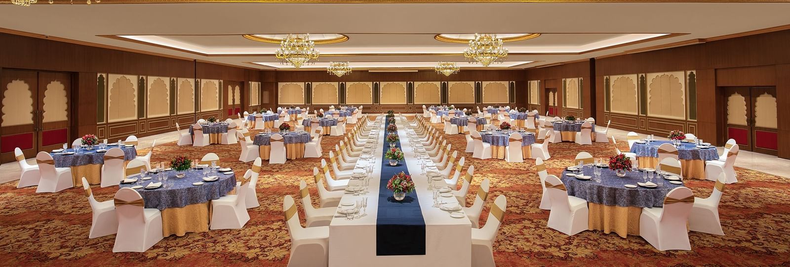 A spacious banquet hall with round tables and chairs, all covered with decorative cloths for the event at Accord Hotels and Resorts.