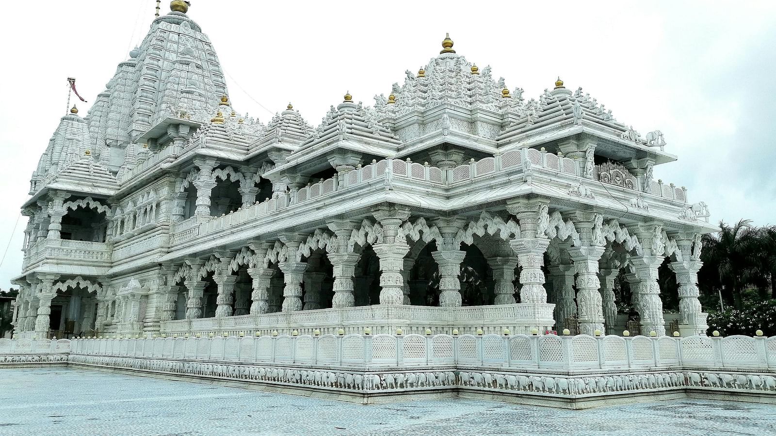 A white marbled temple's facade with white clouds in the background