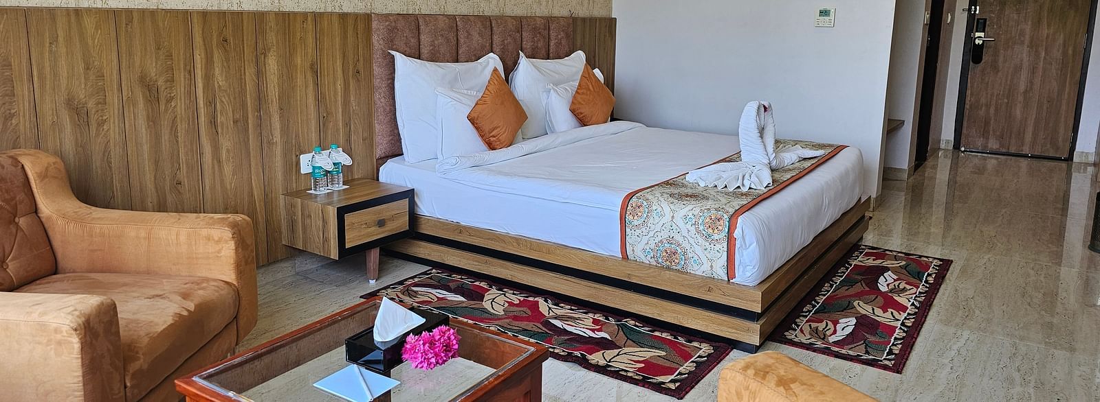 An interior shot of a hotel room at Bamboo Saa Mulberry Resort, with a bed, seating area, and a decorative rug.