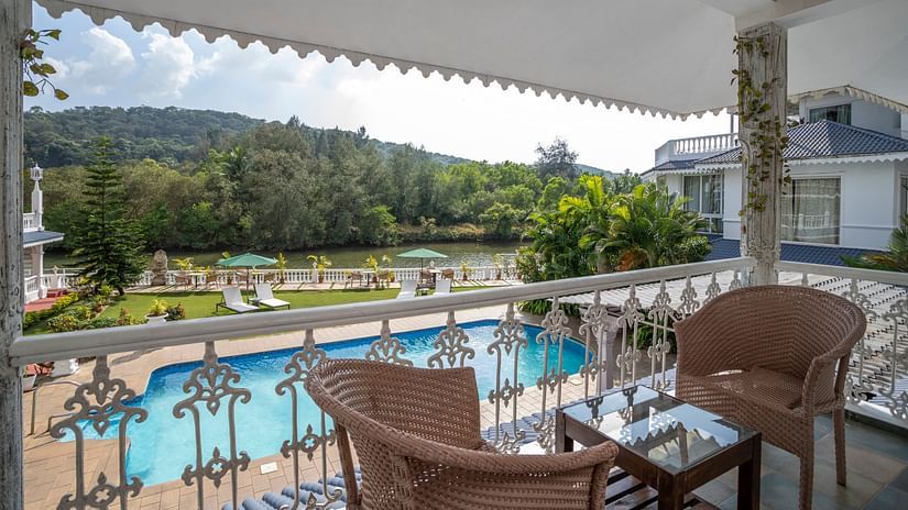 The Maharaj Balcony overlooks the pool and lush green hills - Stone Wood Riverfront Resort, Siolim