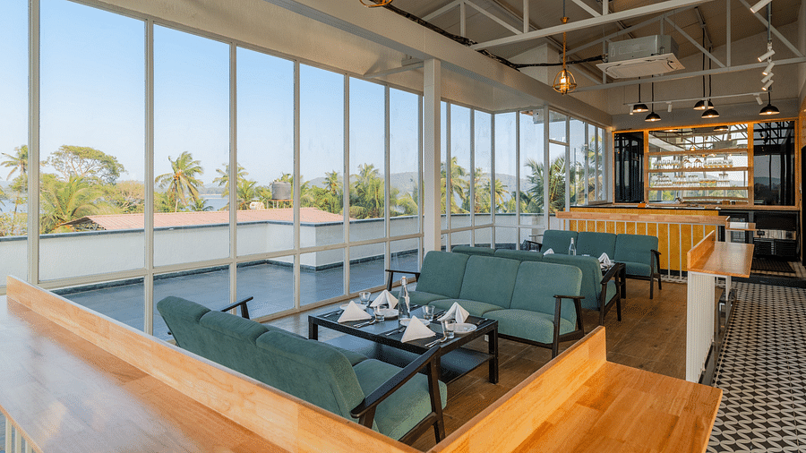 Spacious cafe interior with large windows and comfortable seating at Bedzzz Xclusiv Morjim, Goa