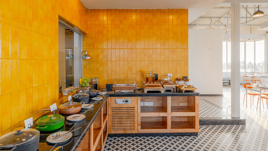 A bright buffet area with vibrant yellow walls and a well-organized food station, inviting guests to indulge in a variety of culinary delights in a cheerful and welcoming environment  at Bedzzz Xclusiv Morjim, Goa