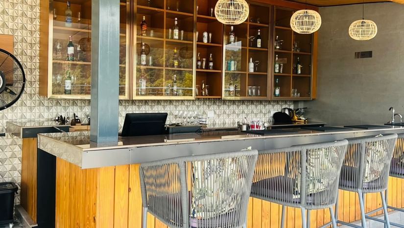 Clove bar at ABN Sarovar Portico, Jim Corbett with rows of metal high stool aligned in front of a yellow desk.