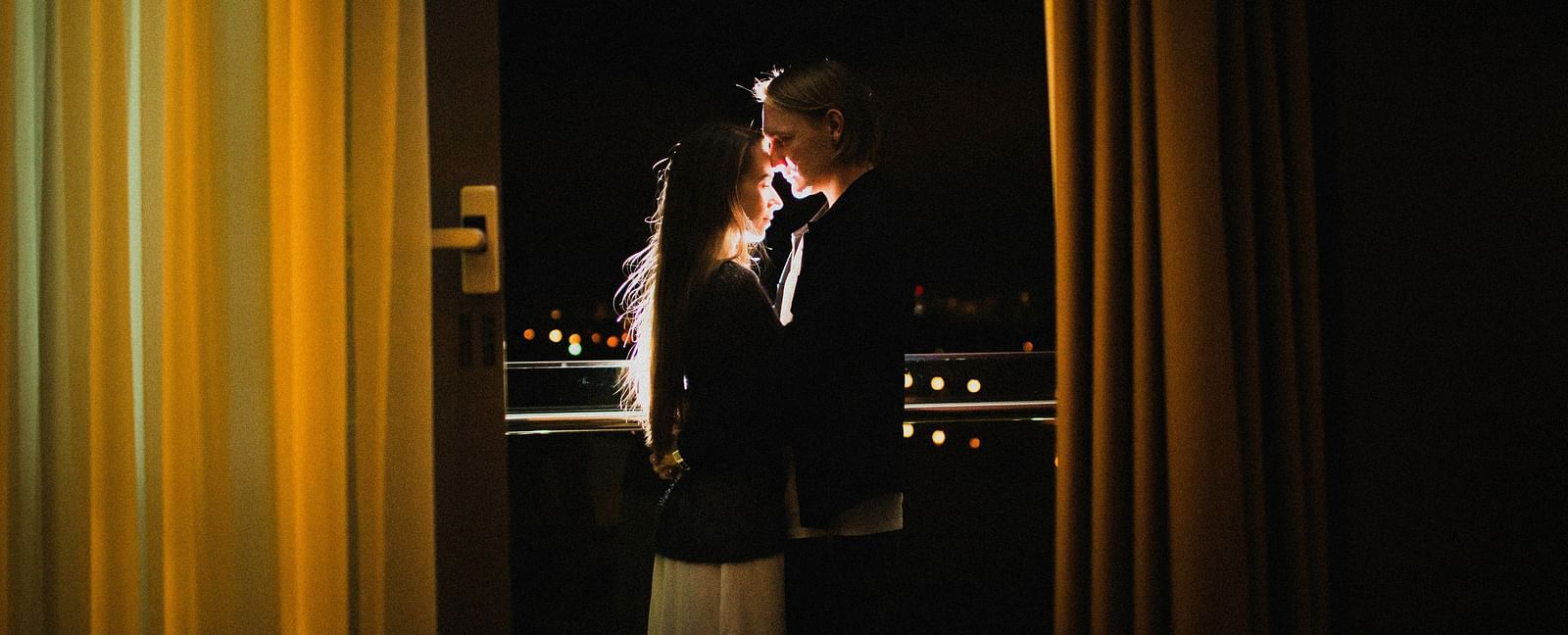 A couple's silhouette in view with light behind them inside a hotel room