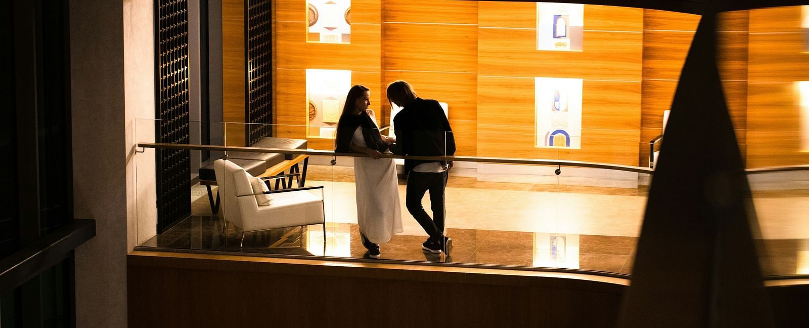A far out view of a couple standing and having an intimate conversation in a balcony of a hotel