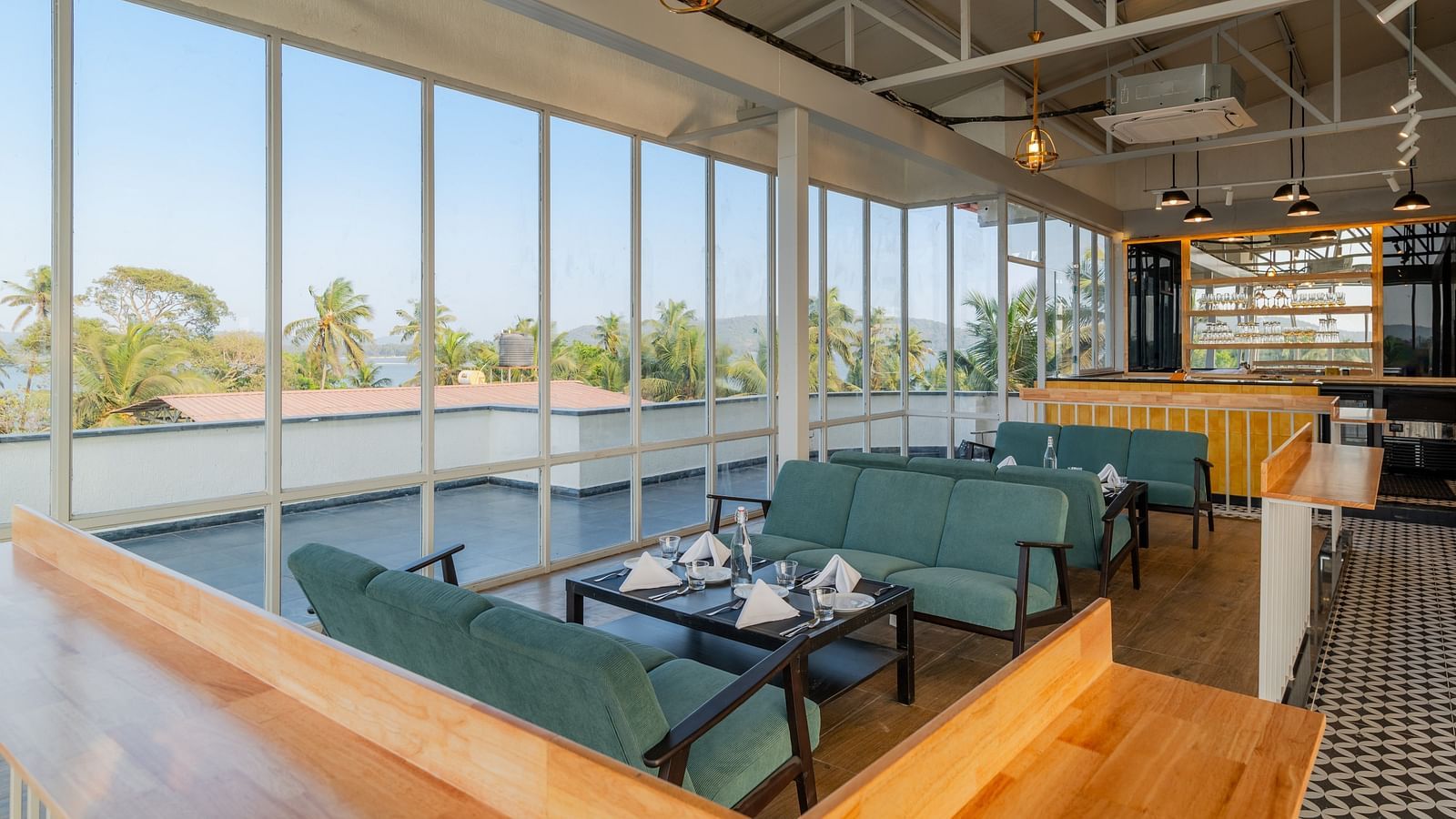 Spacious cafe interior with large windows and comfortable seating at Bedzzz Xclusiv Morjim, Goa
