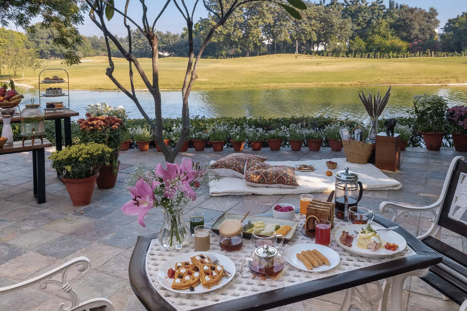 Outdoor dining table set with food and drinks near a lawn at Karma Chalets.