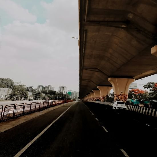 Empty highway under a flyover with minimal traffic and buildings in the distance.