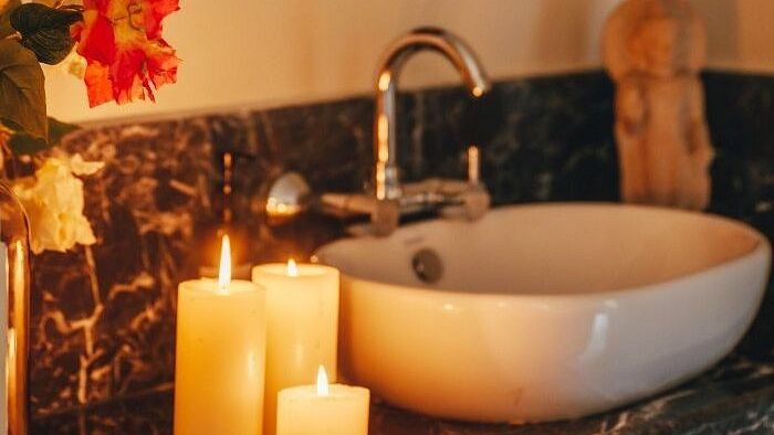 Wash basin with lit candles and a Buddha wall hanging above, placed in a softly lit space at Karma Chalets.