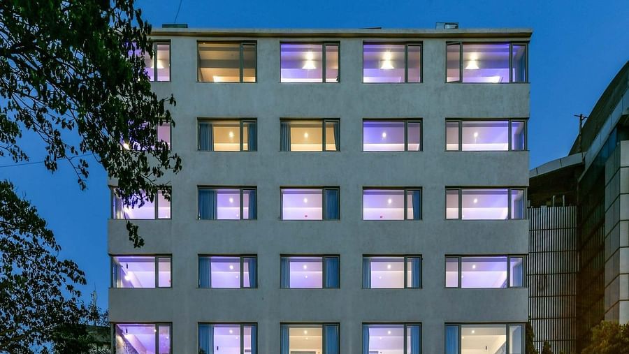 A facade view of Indie Stays, BKC Kalina, illuminated against the night sky.