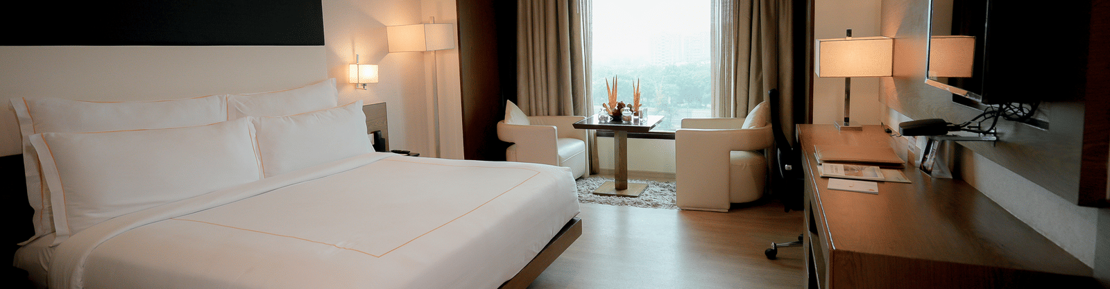 Spacious guest room with large bed, seating area, and a TV setup – Narayani Heights Hotel & Resorts