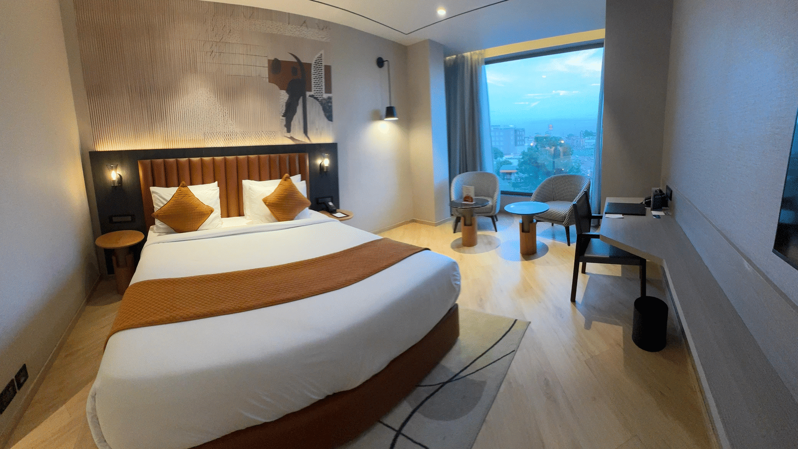 Well-appointed hotel room with a large bed, side tables, lighting, and a window offering an outside view at Ramada Encore by Wyndham Chandigarh Zirakpur.