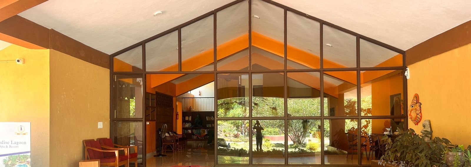 The front entrance to Paradise Wild Hills Resort, Kollur, with a modern, glass-fronted lobby and a red carpet.