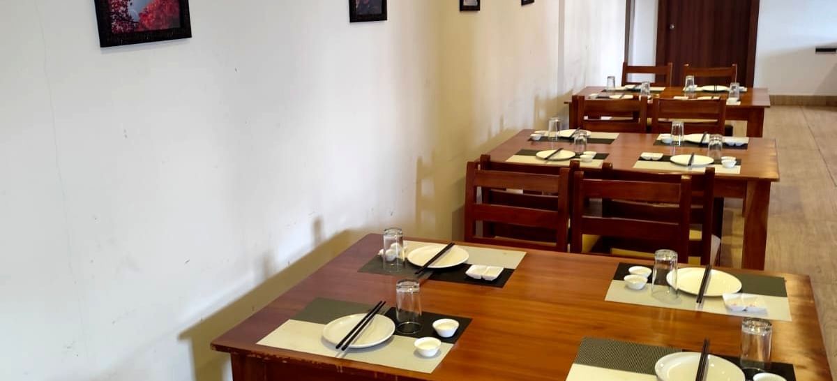 Side view of the Ajito restaurant featuring wooden dining tables with cutlery arranged over it at Ilara Hotels & Spa, Tada.