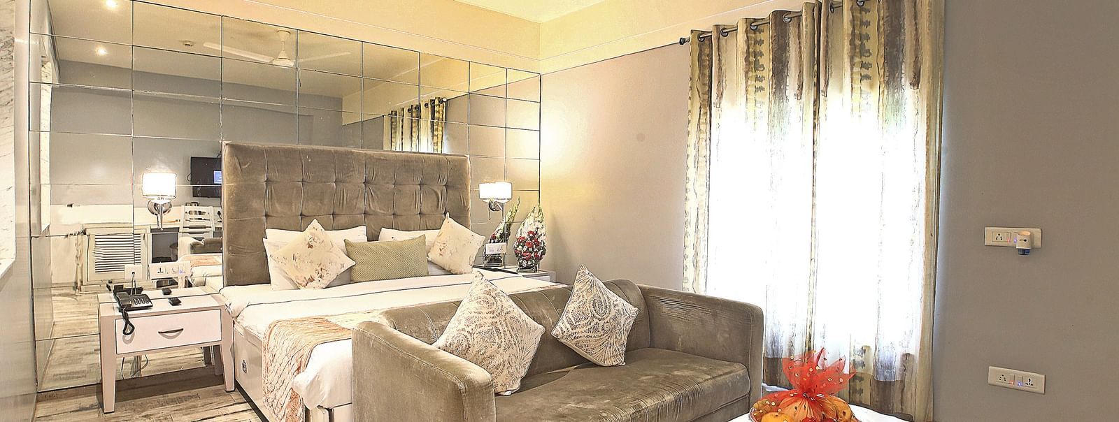 Elegant room with a large bed, table, sofa, chairs, and TV unit at Hotel Emerald, Chandigarh