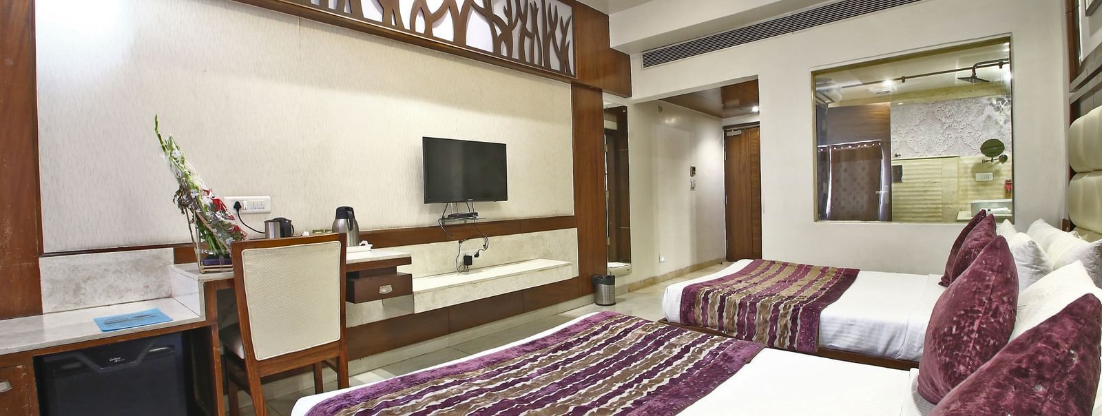 Elegant room with two double beds, table, chair and TV unit at Hotel Emerald, Chandigarh