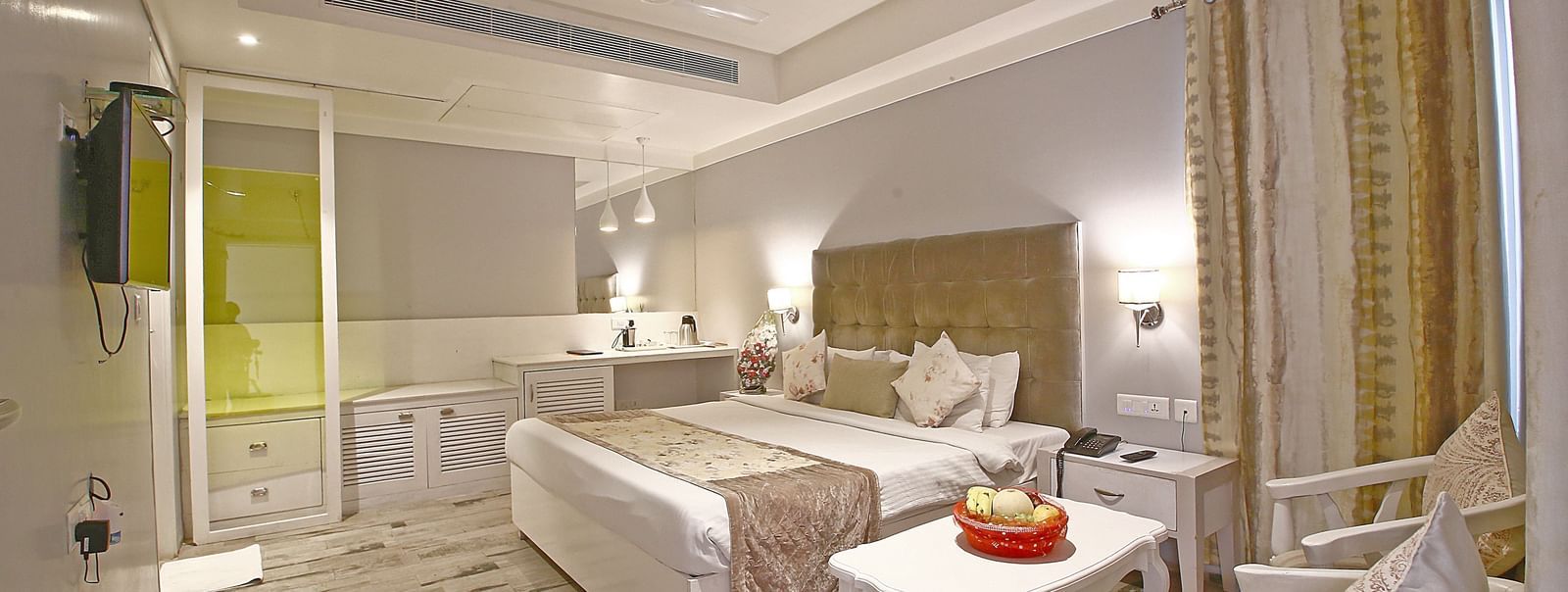 Elegant room with a large bed, table, chairs, and TV unit at Hotel Emerald, Chandigarh