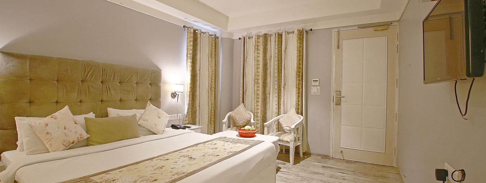 Elegant room with a large bed, table, chairs, and TV unit at Hotel Emerald, Chandigarh