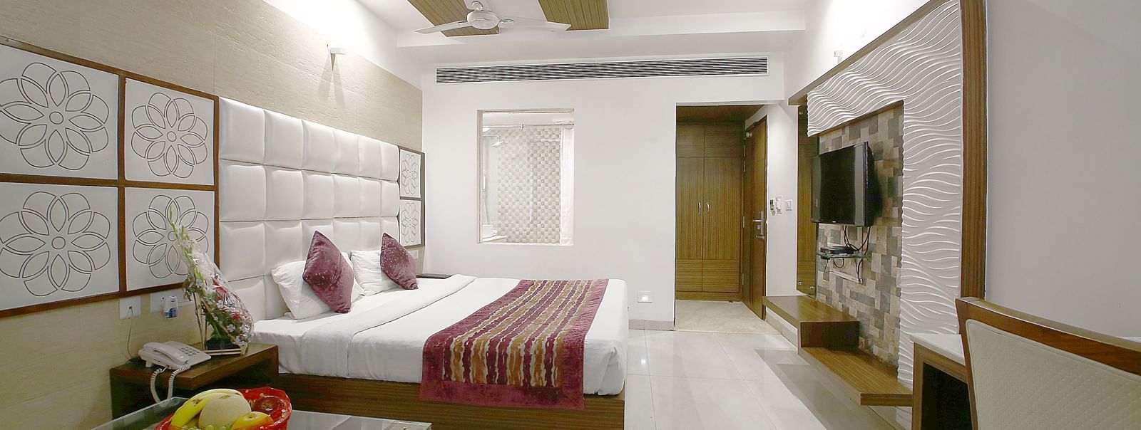 marble floored room with a large bed, table, chair and TV unit at Hotel Emerald, Chandigarh
