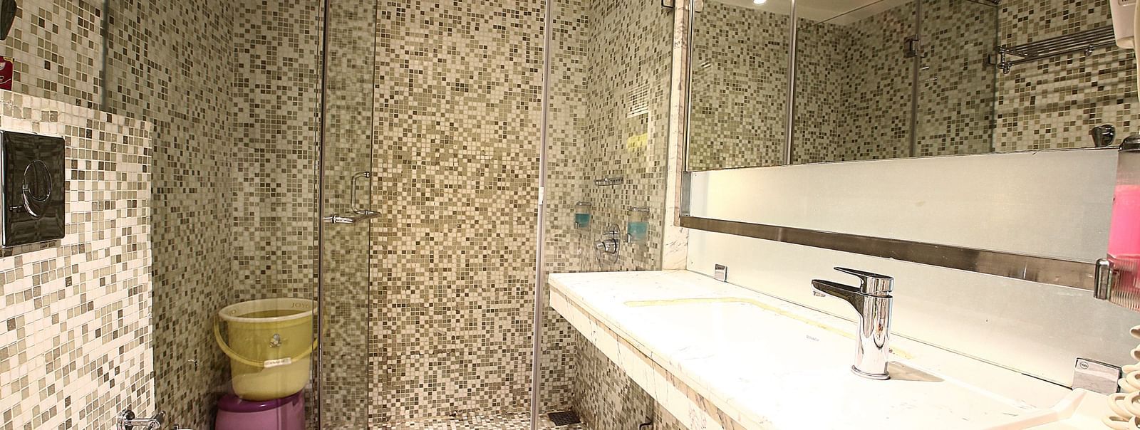 well lit bathroom with a wide mirror, sink, commode and a shower with glass door