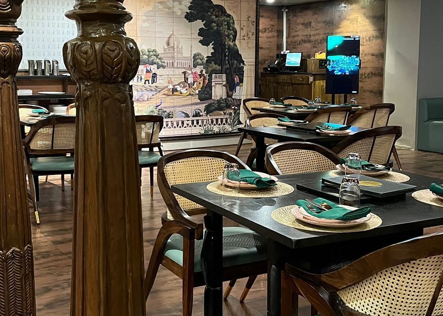 Elegant restaurant interior featuring set tables with place settings, ornate columns, and a large mural on the back wall - Astra Hotels & Suites, Spice Garden Layout