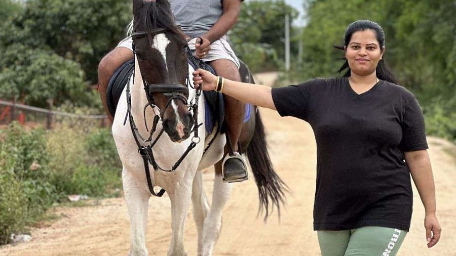 A man on a horse with a helmet at Ravishing Retreat as the horse is being guided by a woman instructor