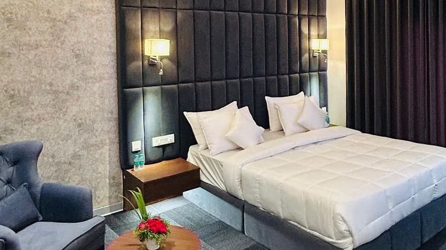 image of the premium room showcasing a common seating area and a plush double bed at Eminence The Corbett