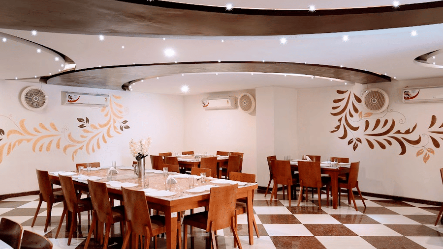 dining corner displaying a long dining table set, floral wall murals, and checkered flooring.