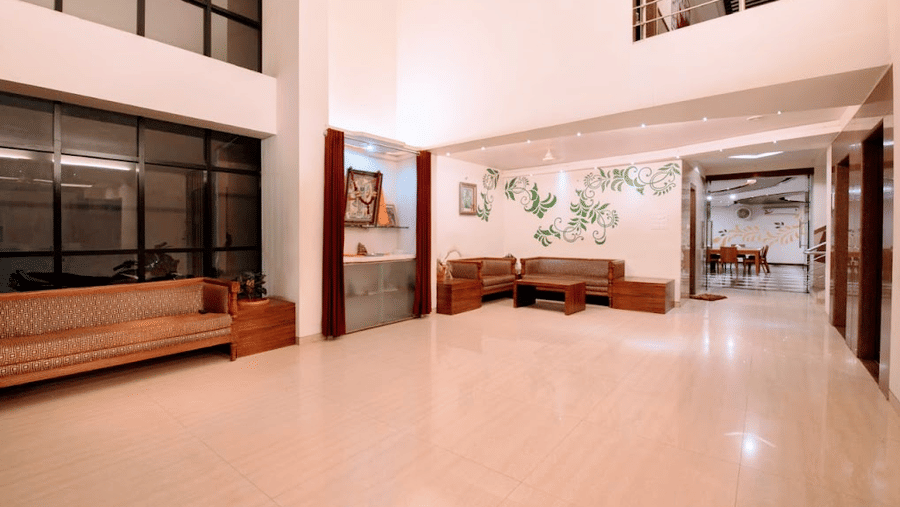 Wide view of a hotel lobby lounge area showing a wooden bench, tiled floors, and a distant sofa seating layout.