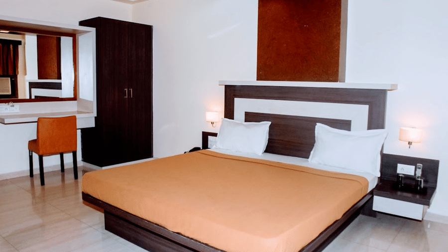Executive room featuring orange bedding, a dark wood wardrobe, and a dressing mirror vanity desk.