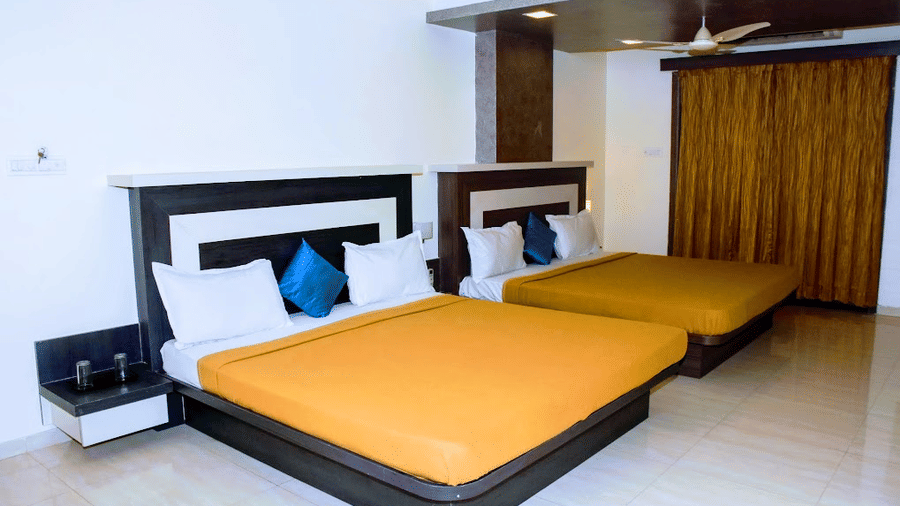 Spacious family room layout with two queen beds featuring bright orange linens and blue accent pillows.
