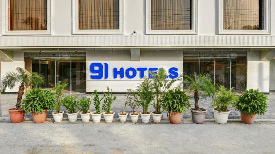  sign board placed behind several potted plants reading '91 Hotels' at Hotel 91 Privé, Gurugram.