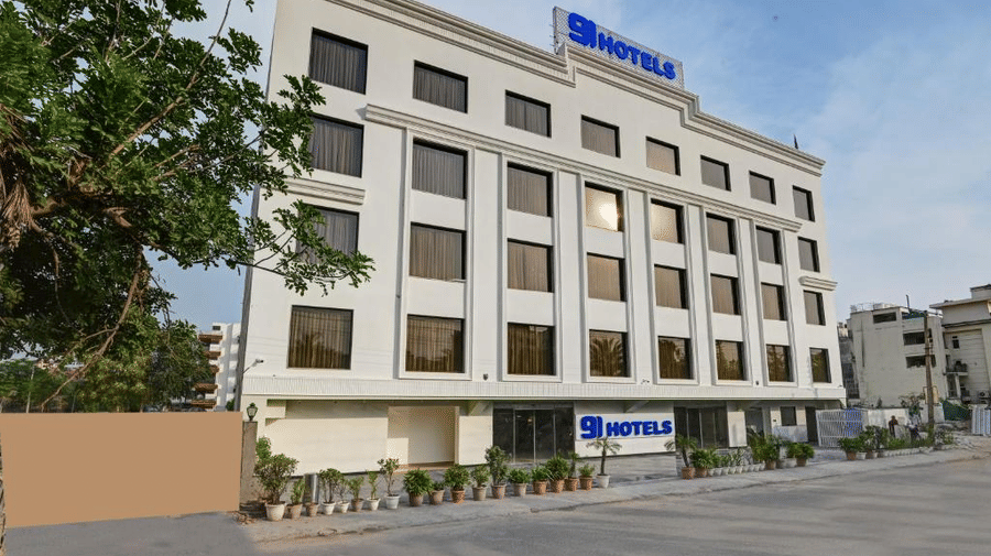 A side-angle view of the facade of Hotel 91 Privé, Gurugram, with an empty driveway in front of a 4-storey building.