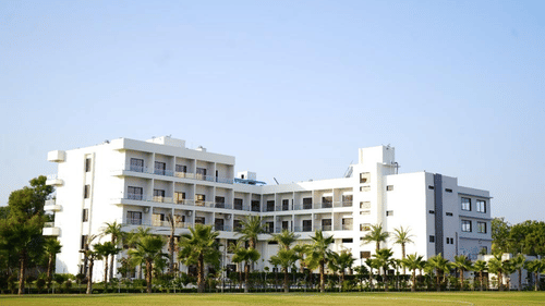 A daylight exterior view of the Arawali Ananta Elite Jaipur hotel building with a green lawn in the foreground.