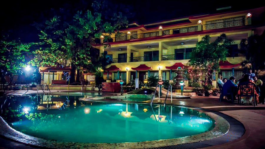 A night view of the pool and the hotel building behind it.