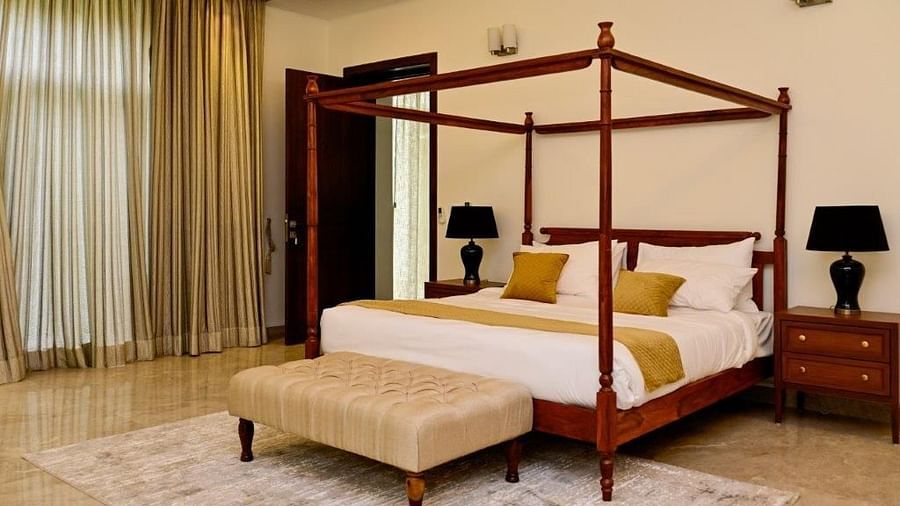 Image of a furnished room with a traditionally designed king size bed, mood lights and a bed side table with a lamp | Udman Luxe Villa