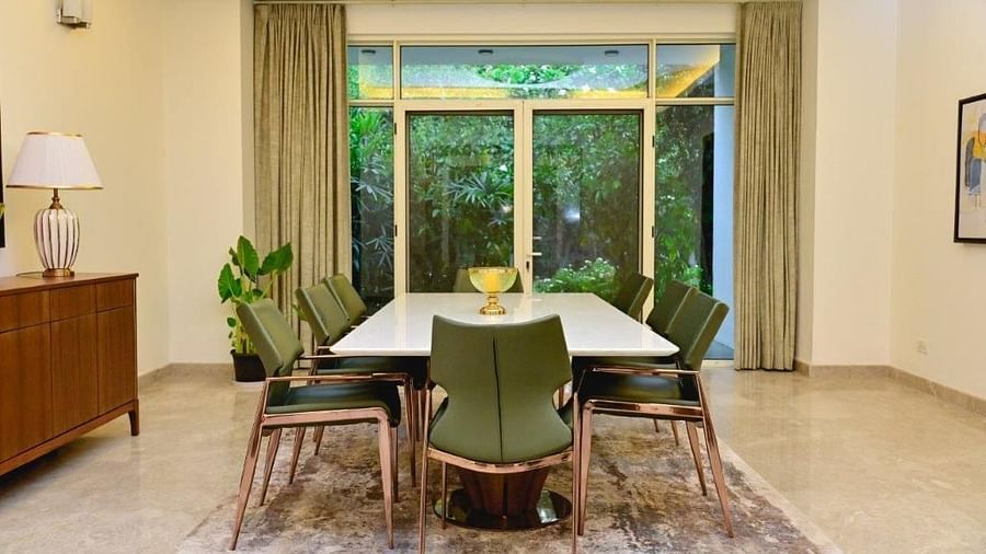 Another shot of the dining room at the villa featuring a white table with green chairs around and an expansive window| Udman Luxe Villa