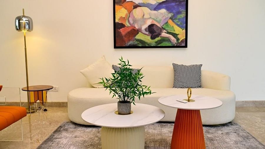 Image of a white couch at the living room of our villa along with two round tables, a lamp and an artificial plant for decor | Udman Luxe Villa