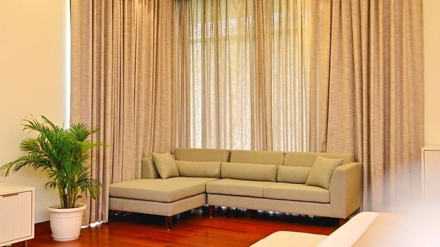 Image of a cream coloured sofa with pastel coloured curtains on the window and an indoor plant  | Udman Luxe Villa