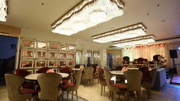 A dining setup with multiple round tables and chairs under an ornately decorated ceiling.