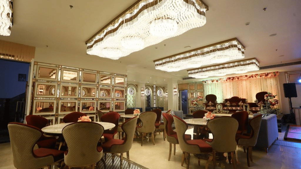A dining setup with multiple round tables and chairs under an ornately decorated ceiling.