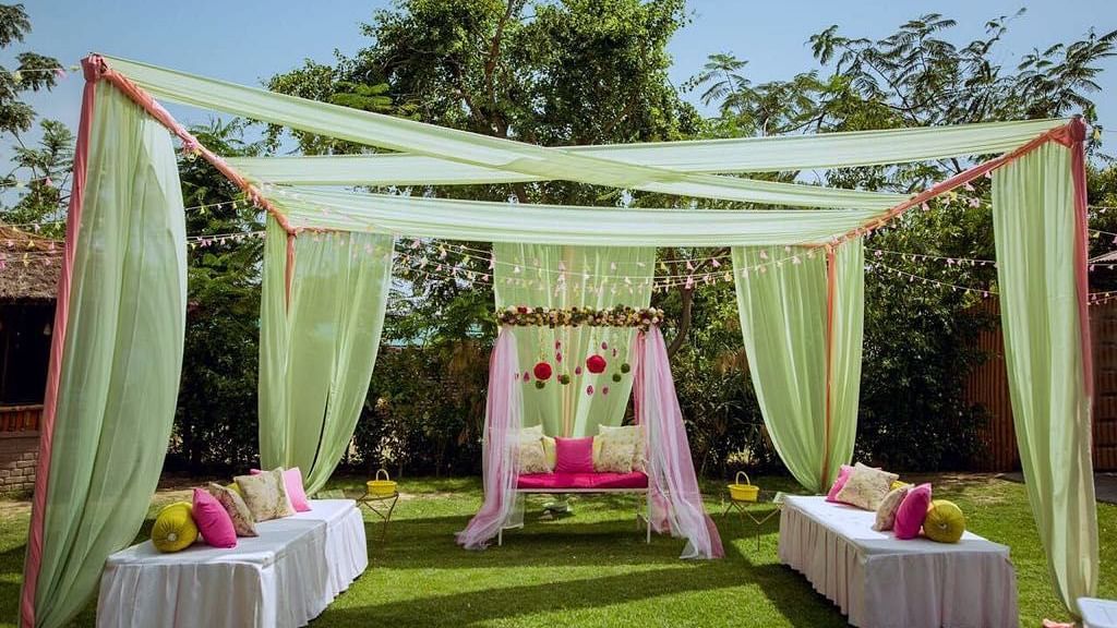 An image of a well decorated stage with fabric pieces and flowers with seating area in all three sides in the garden