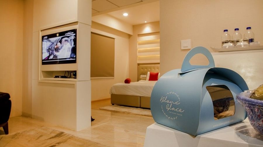 Sitting area of the suite room with a packet of food on the table, a television mounted on the wall and door leading to the bedroom  Art Boutique Hotel, Hyderabad