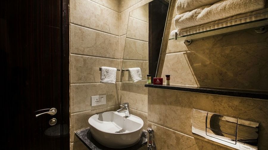 Standard room bathroom with sink, and towel on the wall at Art Boutique Hotel, Hyderabad